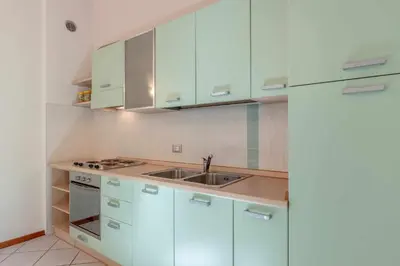 a kitchen with white cabinets and a sink at Appartamento al Bosc Grauno Ospitar in Grauno