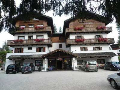 a large building with cars parked in a parking lot at Hotel Principe in Cortina dʼAmpezzo