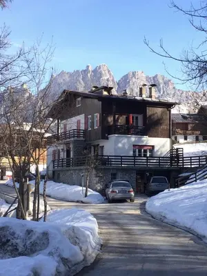 a house with two cars parked in the snow at B&B Cristallo in Cortina dʼAmpezzo