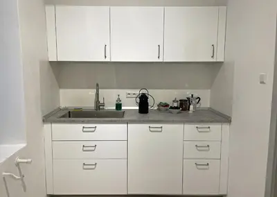 a kitchen with white cabinets and a sink at Rosa Apartments City Center in Merano