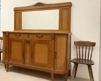 a wooden cabinet with a mirror and a chair at Rosa Apartments City Center in Merano