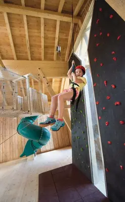 a young girl is on a climbing wall at Familienhotel Huber in Valles