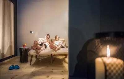 two women laying on a bed in a room at Familienhotel Huber in Valles