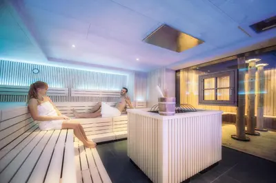 a man and a woman sitting in a sauna at Familienhotel Huber in Valles