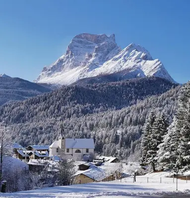 a snow covered mountain with a house in the foreground at Residence Peniè in San Vito di Cadore