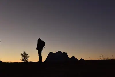 a person with a backpack standing on a hill at sunset at Residence Peniè in San Vito di Cadore