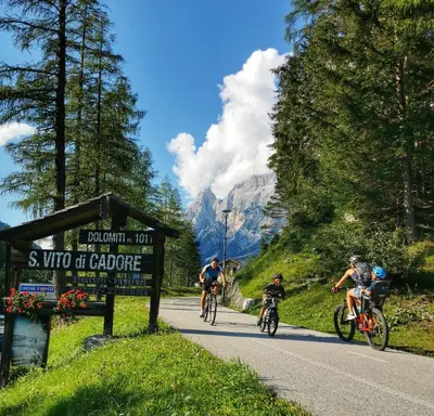 a group of people riding bikes down a road at Residence Peniè in San Vito di Cadore