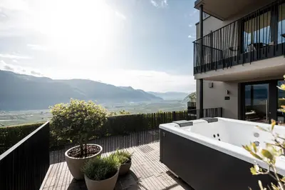 a bath tub sitting on a deck next to a building at My Spring - Panoramic Suites in Lana