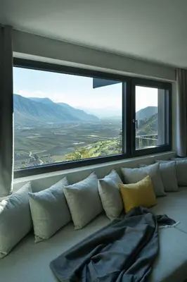 a couch with pillows in front of a large window at My Spring - Panoramic Suites in Lana