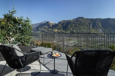 two chairs and a table on a balcony with mountains at My Spring - Panoramic Suites in Lana