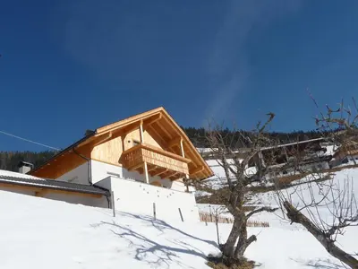 a building with a wooden roof in the snow at Lü de Rü in San Vigilio Di Marebbe