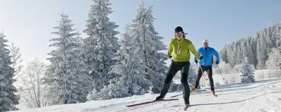 two men are skiing down a snow covered slope at Lü de Rü in San Vigilio Di Marebbe