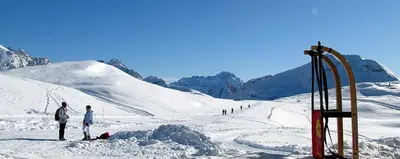 two people standing in the snow next to a ski lift at Lü de Rü in San Vigilio Di Marebbe