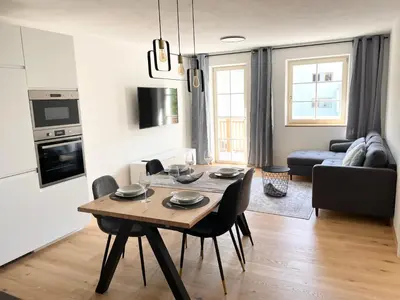 a kitchen and living room with a table and chairs at Rosa's Boutique Apartment in Merano
