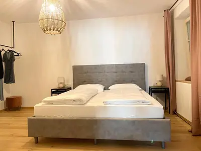 a bedroom with a large bed with a gray headboard at Rosa's Boutique Apartment in Merano