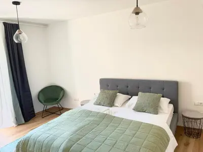 a bedroom with a bed with a green blanket and a chair at Rosa's Boutique Apartment in Merano