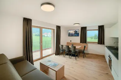 a living room with a couch and a table with chairs at Appartments Lindenhof in Riscone