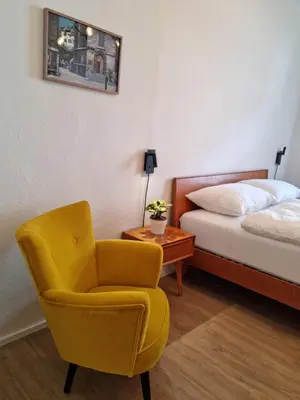 a bedroom with a yellow chair and a bed at Rosa Rooms Meran in Merano