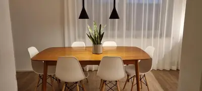 a dining room table with white chairs and a vase with flowers at Rosa Rooms Meran in Merano