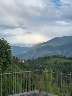 a rainbow over a valley with a fence at Noan Panorama Suiten - Arendt in San Genesio Atesino