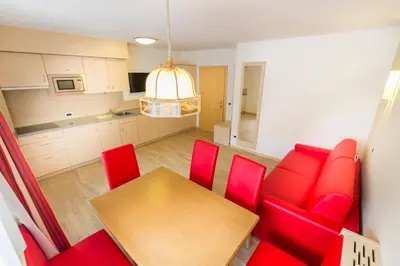 a kitchen and dining room with red chairs and a table at Apartments Diamant in Ortisei