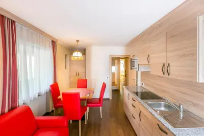 a kitchen with red chairs and a table at Apartments Diamant in Ortisei