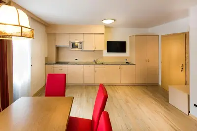 a kitchen with a wooden table and red chairs at Apartments Diamant in Ortisei