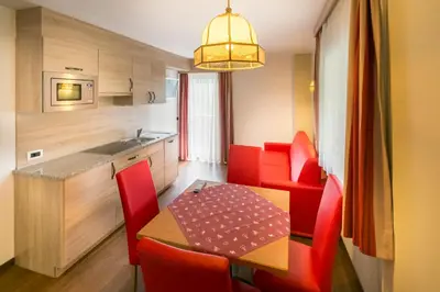 a small kitchen with a table and red chairs at Apartments Diamant in Ortisei