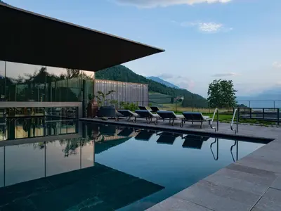 a swimming pool with lounge chairs next to a house at Manna Resort in Montagna