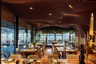 a restaurant with tables and chairs and a large window at Manna Resort in Montagna