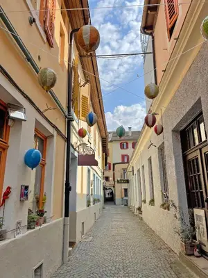 a narrow alley with buildings and blue balloons on the buildings at Rosa Apartment with parking historic city center in Merano