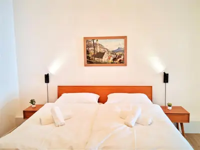 a bedroom with two white beds and a painting on the wall at Rosa Apartment with parking historic city center in Merano