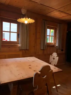 a wooden table and chairs in a room with windows at Ringgelinhof Onach in San Lorenzo di Sebato