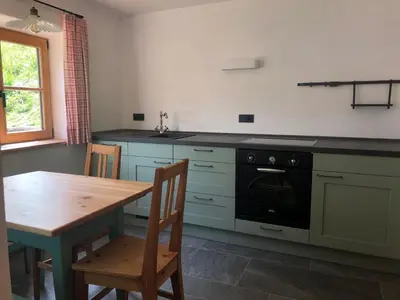 a kitchen with a wooden table and a black oven at Ringgelinhof Onach in San Lorenzo di Sebato