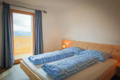 a bed with blue pillows in a room with a window at Zolerhof in Feldthurns