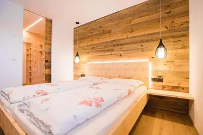 a bedroom with a wooden wall and a bed at Zolerhof in Feldthurns