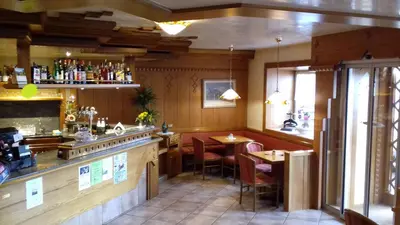 a bar in a restaurant with tables and chairs at Albergo Alpino in Arabba