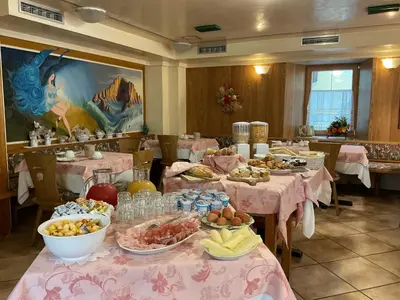 a dining room with tables filled with food at Albergo Alpino in Arabba