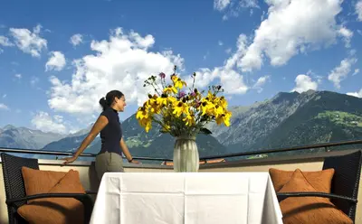 a woman standing on a balcony with a vase of flowers at mittendorf klimaresidence in Schenna