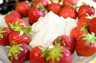 a plate of strawberries with whipped cream on it at mittendorf klimaresidence in Schenna