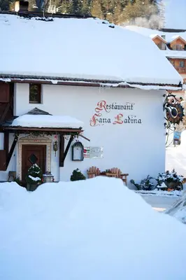 a building covered in snow with a sign on it at La Ücia by Fana Ladina in San Vigilio Di Marebbe