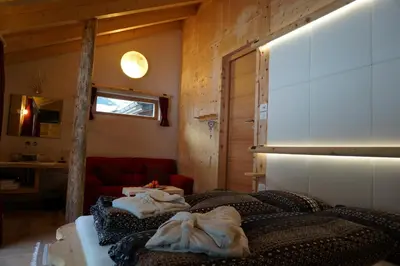a room with three beds and a red couch at La Ücia by Fana Ladina in San Vigilio Di Marebbe