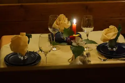 a table with wine glasses and a candle on it at La Ücia by Fana Ladina in San Vigilio Di Marebbe