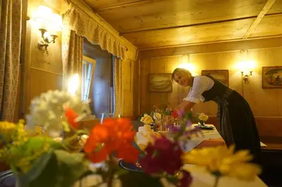 a woman standing over a table with flowers on it at La Ücia by Fana Ladina in San Vigilio Di Marebbe