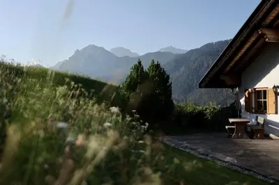 a house with a picnic table and mountains in the background at Apartments Ciastel in San Vigilio Di Marebbe
