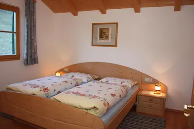 a wooden bed in a bedroom with two lamps at Villa Anna in Siusi