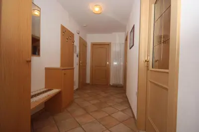 a hallway with wooden doors and a tiled floor at Villa Anna in Siusi