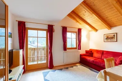 a living room with a red couch and windows at Villa Anna in Siusi