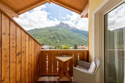 a balcony with a table and a view of a mountain at Majon d'Aisciuda in Vigo di Fassa