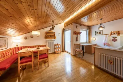 a living room with a wooden ceiling and a table and chairs at Majon d'Aisciuda in Vigo di Fassa